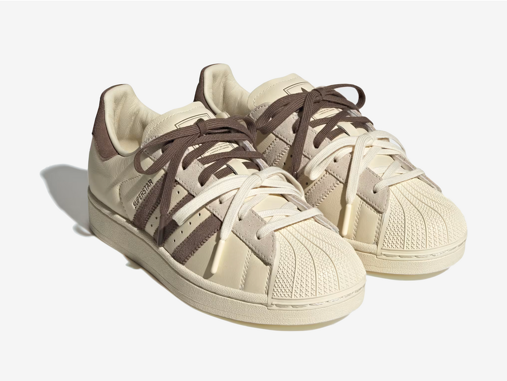 The Adidas Superstar Molly-Mae Latte reworks the classic silhouette with a clean, minimal aesthetic. Built with a leather upper, signature shell toe, and durable rubber sole, the shoe maintains its heritage design while feeling more contemporary. Finished in warm beige and cream tones with subtle branding, it delivers a neutral, versatile look suited to everyday styling.