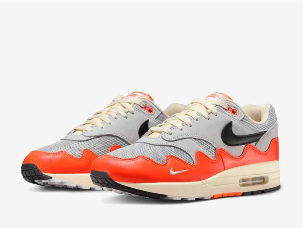 The Patta x Nike Air Max 1 “Orange Grey” reimagines a classic with the signature wave-rippled mudguard from the iconic Waves pack. Hyper Crimson accents reference Dutch national pride, while Pure Platinum and natural white tones keep the upper clean and wearable. Finished with smooth leather overlays and a gold bracelet featuring Swoosh detailing and the Surinamese flag, it blends heritage with modern streetwear style.