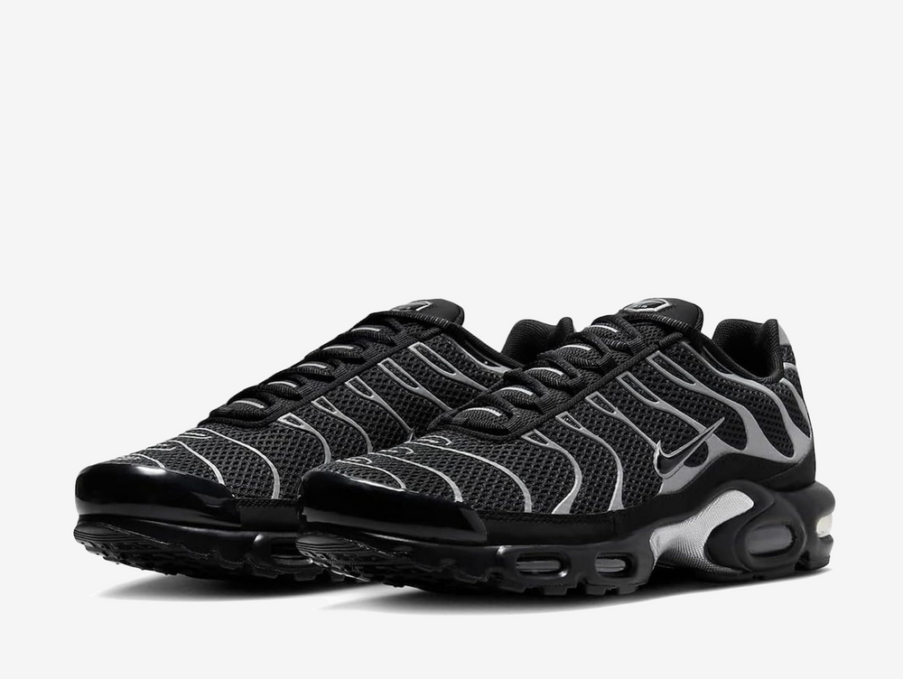 This sleek Tuned 1 flaunts a blacked-out open mesh upper with a plastic toe cap and synthetic mudguard for a lightweight, breathable ride. The Swoosh, metallic silver TPU overlays, and nylon eyelets are fully reflective, allowing the wavy panels to stand out atop the all-black background. A hallmark yellow TN logo adorns the heel, complementing the Nike emblem on the leather tongue.