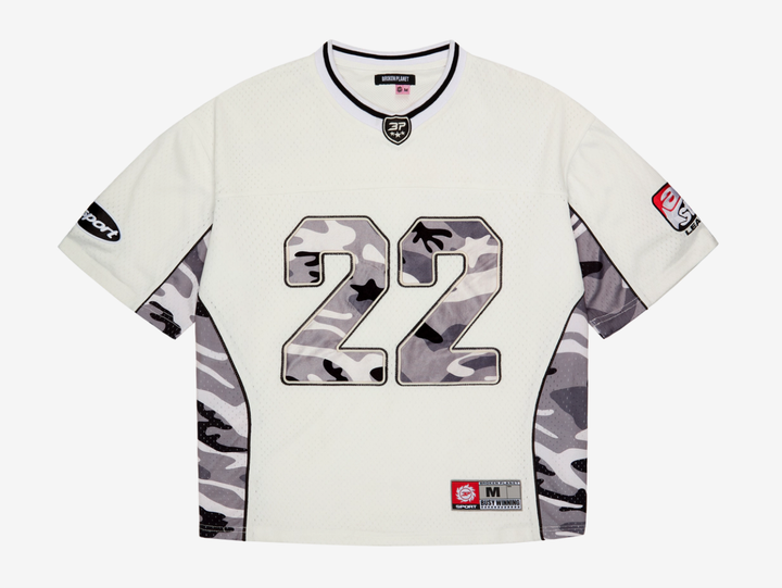 A standout piece built with a premium recycled polyester mesh construction, finished with satin camo appliqué embroidery across the chest and back for a layered, textured look. Detailed with sleeve patches, a woven label, and embroidered neck patch, combining classic sportswear references with elevated finishing throughout. Designed with a true-to-size fit for everyday wear, we recommend taking your usual size.
