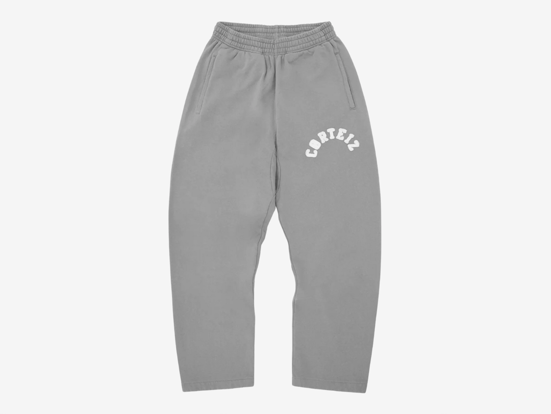 Crafted from heavyweight 440GSM 100% cotton with a soft fleece-lined interior, the Corteiz Colly Arch Logo Sweatpants deliver premium comfort and everyday durability. Designed with coverstitch detailing throughout, they feature a raw edge Corteiz RTW logo on the left leg, an adjustable drawstring with an elasticated waistband, and a practical rear pocket. Finished with an open hem and a true-to-size fit, these sweatpants offer a clean, relaxed silhouette with signature Corteiz styling.