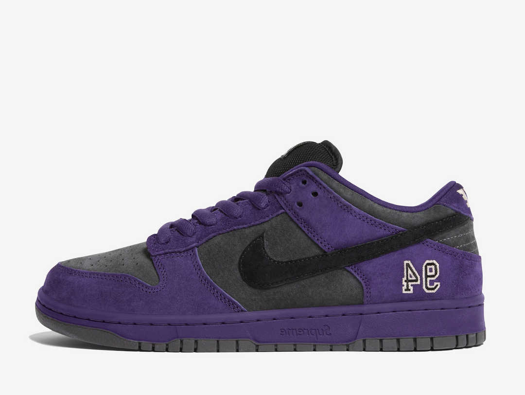 This skate shoe features a dark grey suede upper with a black Swoosh and purple accents. An embroidered “94” on the lateral foxing nods to the brand’s Manhattan origins, while a debossed Supreme label, co-branded sockliners, and orange hangtag add signature touches. Classic SB details appear on the heel tabs and puffy tongue, with Zoom cushioning in the heel for impact protection. Extra black laces offer versatile styling for skate or casual wear.
