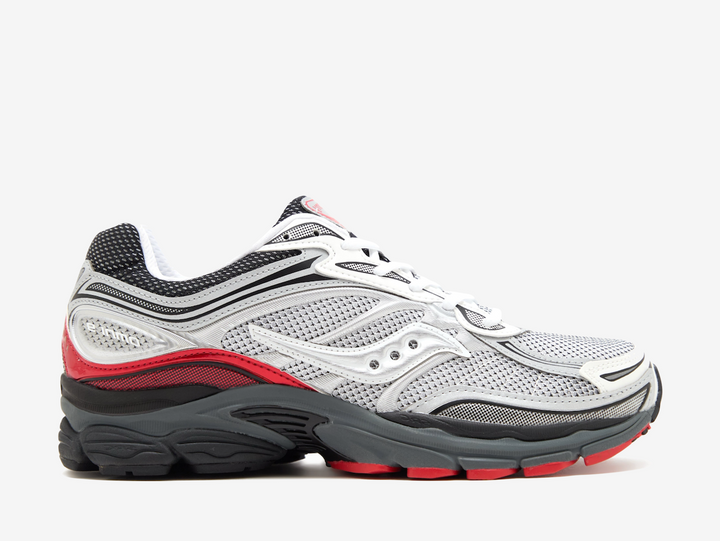 The Saucony ProGrid Omni 9 Light Grey features a breathable grey mesh upper with layered silver overlays, black detailing and bold red accents across the heel and outsole. Underfoot, the chunky black midsole combines Saucony’s ProGrid cushioning with a durable rubber outsole, giving the pair a comfortable feel and distinctive retro-running look.