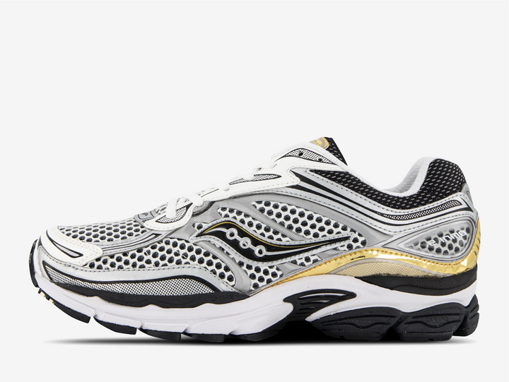 The Saucony ProGrid Omni 9 White Black Silver Gold revisits early two thousands running energy through bold contrast and metallic detail. White and black establish a familiar athletic base, while silver and gold accents introduce shine and depth across the layered upper. The ProGrid structure gives the silhouette presence, emphasizing performance heritage through visible form and proportion.