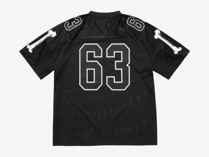 The Supreme Bones Football Jersey Black puts a bold spin on classic athletic wear, merging sport structure with graphic street energy. Made from breathable mesh, it features skeletal-inspired graphics that pop against the clean white base. Striped sleeves and tackle-twill style branding nod to vintage gridiron uniforms, while the relaxed, boxy fit allows easy layering and all-day comfort. A statement piece rooted in sport with unmistakable Supreme attitude.