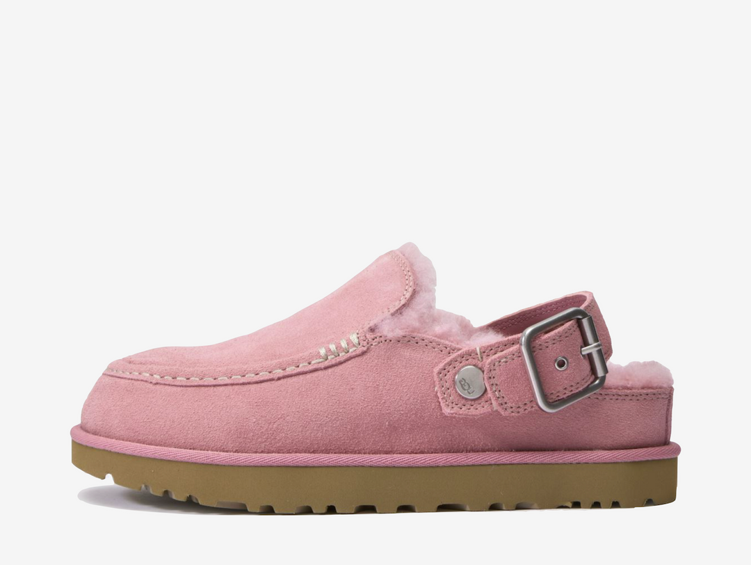 The UGG Goldenstar Evelina Clog Pink features a soft suede upper in a pastel pink finish, complete with decorative stitching and an adjustable heel strap. A plush interior and lightweight EVA outsole provide cushioning and everyday comfort.