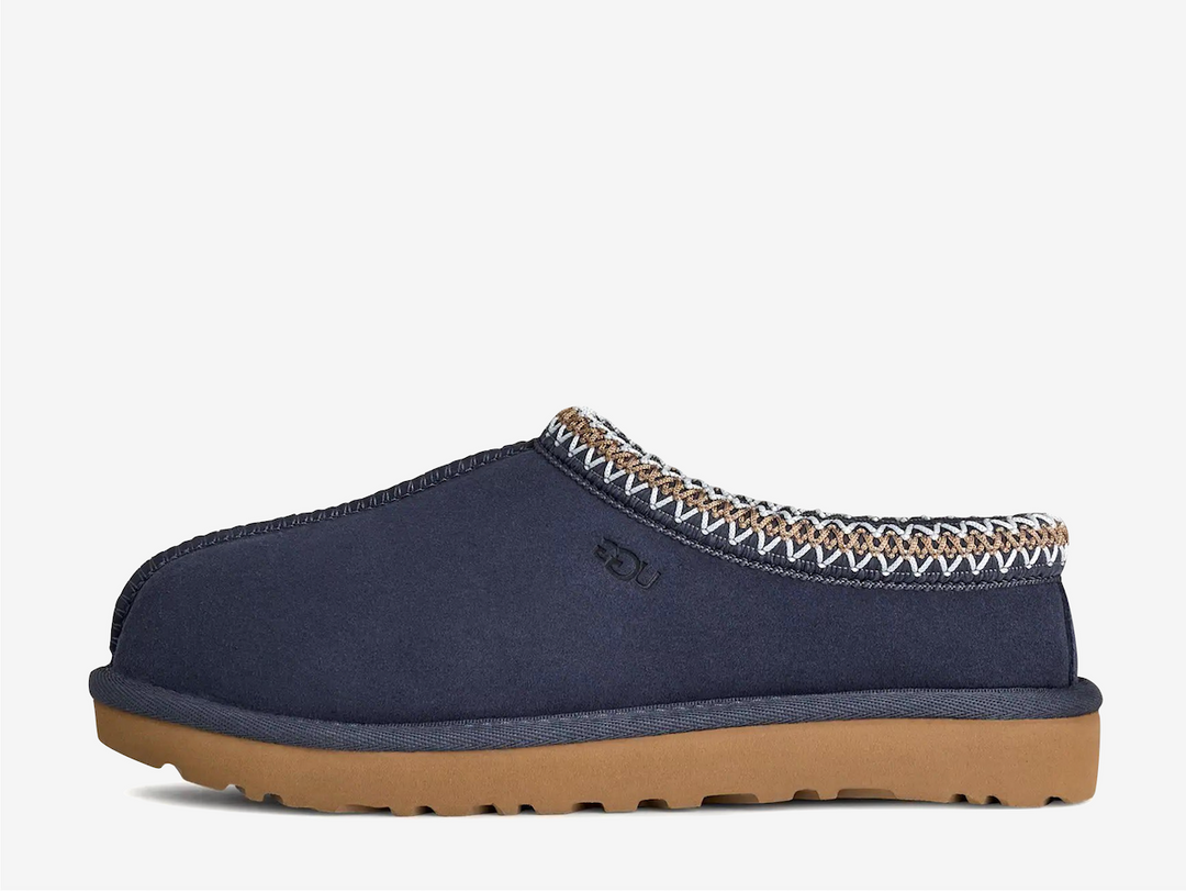 The Tasman II slippers are a sturdy and comfortable slip-on silhouette featuring the same durable outsole as the iconic UGG Classic Boot. Crafted with velvety suede, plush natural wool and embroidered braided detailing. In a classic Navy colourway.