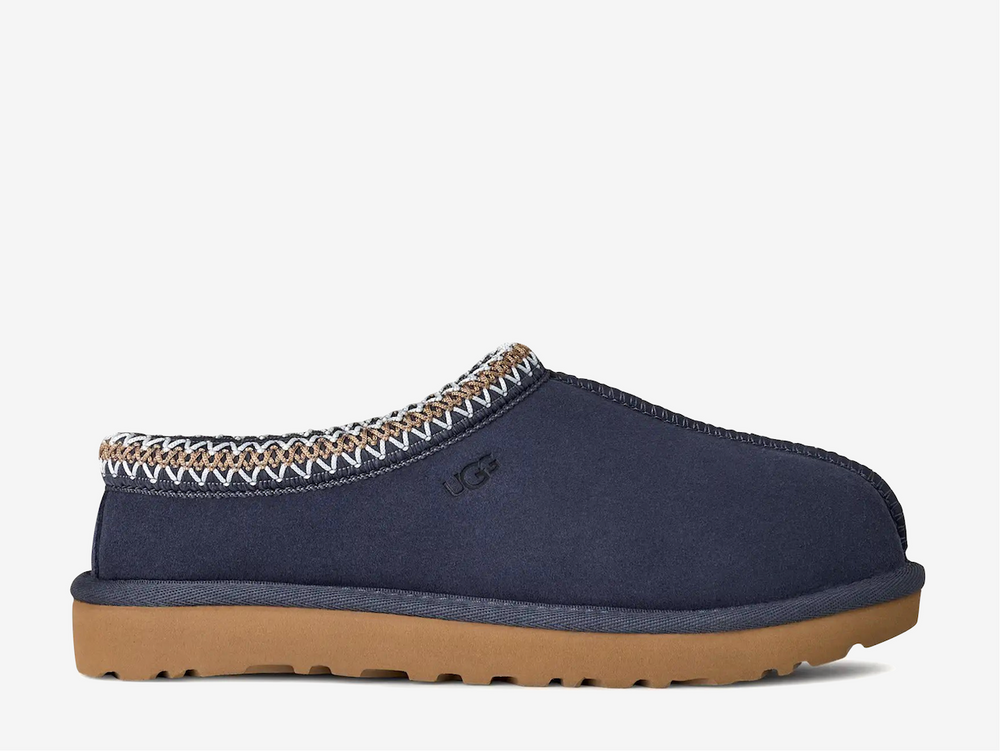 The Tasman II slippers are a sturdy and comfortable slip-on silhouette featuring the same durable outsole as the iconic UGG Classic Boot. Crafted with velvety suede, plush natural wool and embroidered braided detailing. In a classic Navy colourway.