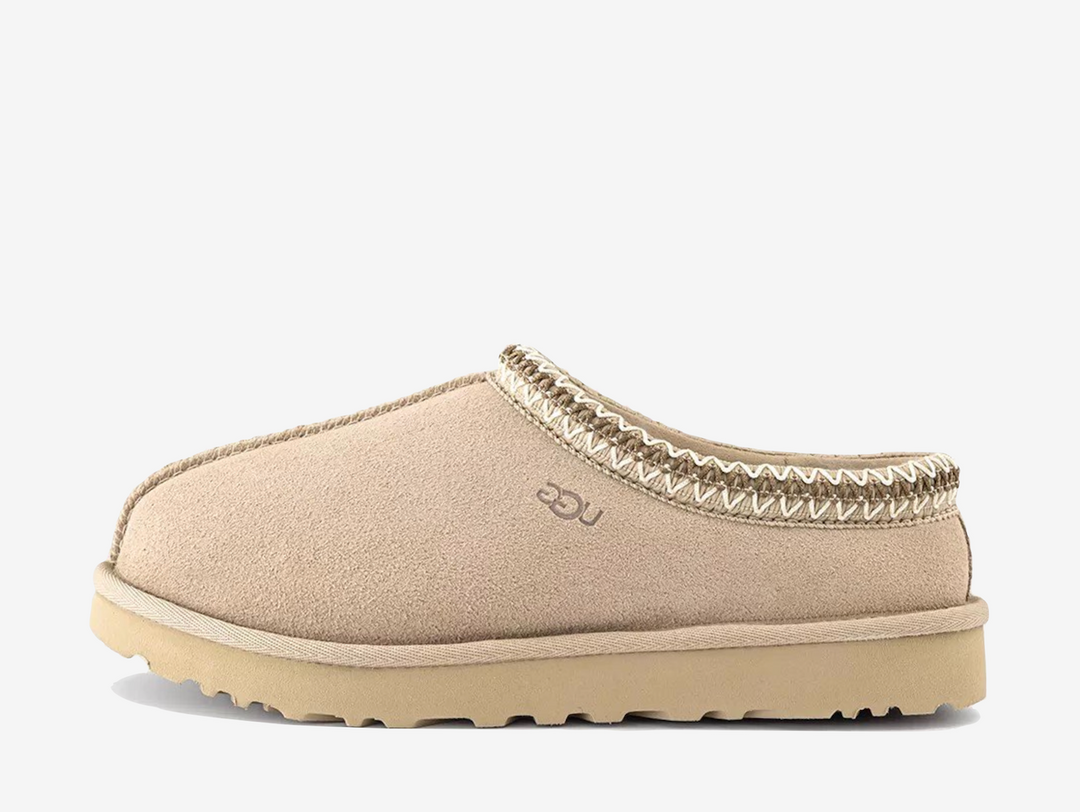 The UGG Tasman Slipper Moonlight features the iconic slip-on silhouette in a clean, light neutral finish. Crafted from soft suede with signature braid detailing and a plush lining, it offers everyday comfort with a versatile look.