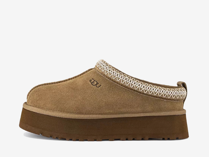 The UGG Tazz Slipper Light Bronze arrives in a warm neutral suede finish with signature woven detailing around the collar. Its plush lining and platform sole provide the familiar comfort of UGG with a more elevated silhouette.