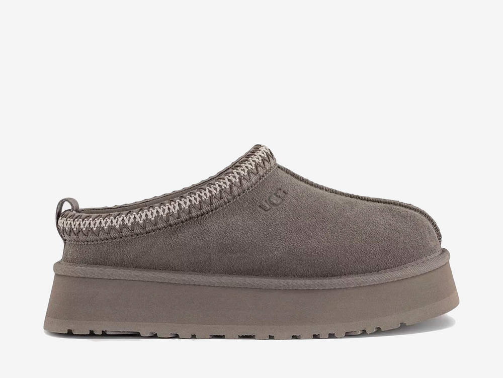 The UGG Tazz Slipper Smoke Plume Sea Salt combines soft grey and neutral tones across its suede upper and signature collar detailing. A plush lining and chunky platform sole complete the pair with warmth, comfort and a distinctive elevated shape.