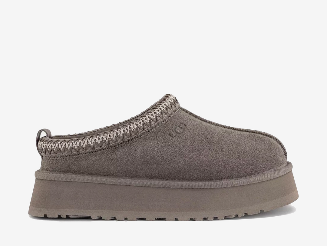The UGG Tazz Slipper Smoke Plume Sea Salt combines soft grey and neutral tones across its suede upper and signature collar detailing. A plush lining and chunky platform sole complete the pair with warmth, comfort and a distinctive elevated shape.